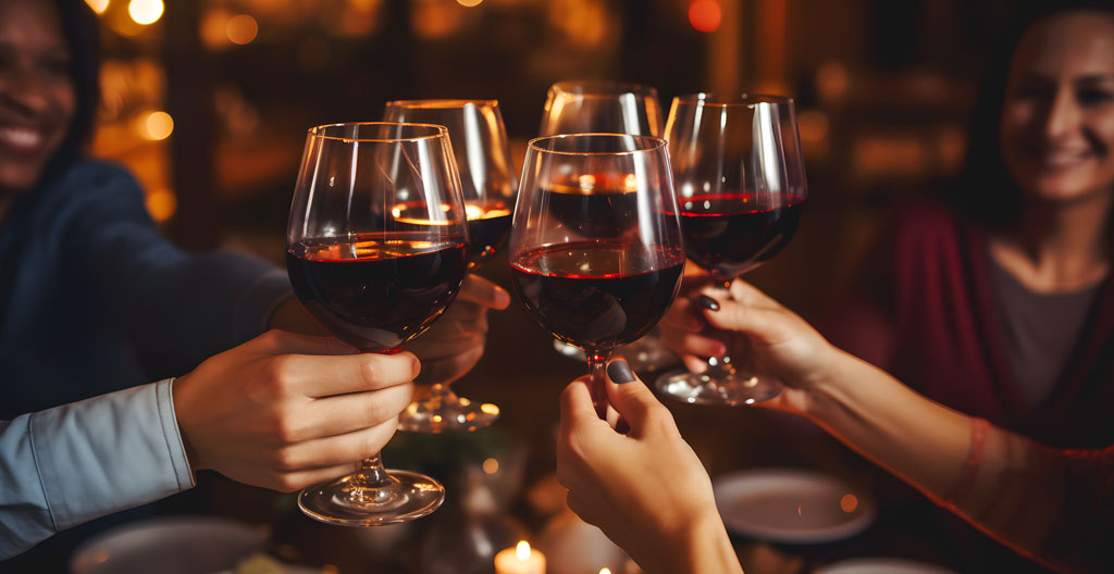 Gros plan sur le bord de deux verres à vin côte à côte sur une table en bois, l'un avec un buvant fin et l'autre plus épais, tous deux contenant du vin rouge